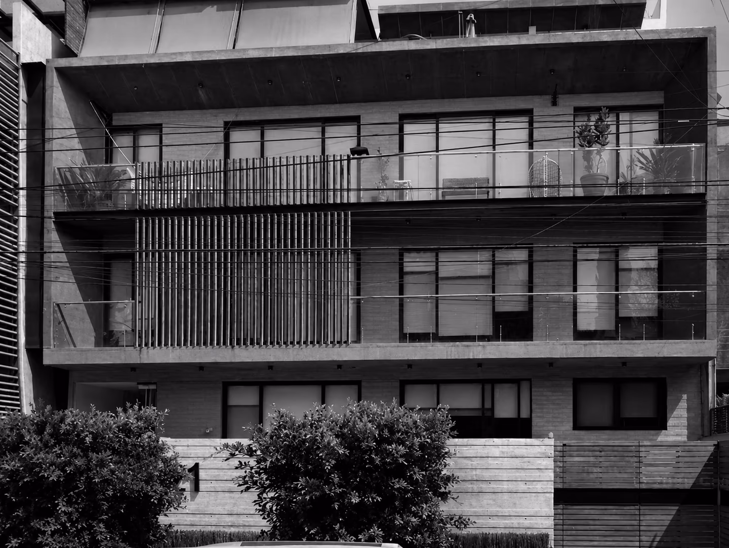 Fachada residencial con balcones y vegetación en blanco y negro